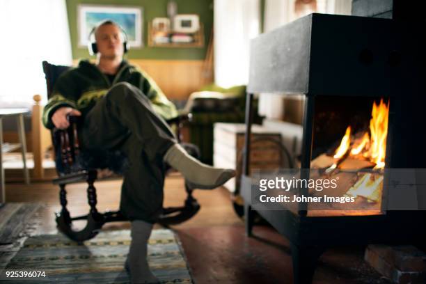 man listening to music next to fireplace - johner images bildbanksfoton och bilder