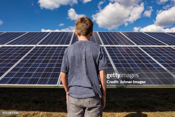 boy standing in front of solar panels - teenager alter photos et images de collection