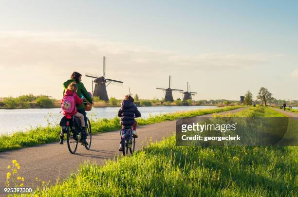 radfahren, vorbei an windmühlen bei kinderdijk in holland - the netherlands stock-fotos und bilder