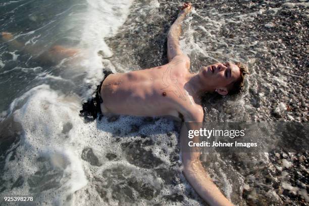 young man lying on seashore - waterline ストックフォトと画像