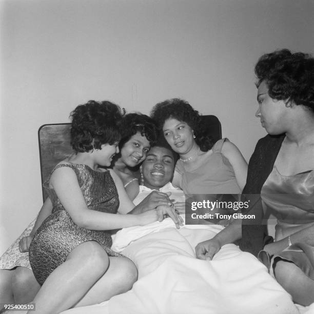 American Heavyweight boxer, Cassius Clay , relaxing in his London hotel room with friends, Brenda Howell, Norma Lindo, Kathleen O"u2019Flaherty and...