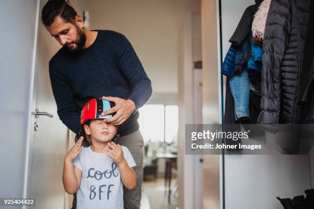 father helping son to put on cycling helmet - father helping son wearing helmet stock pictures, royalty-free photos & images