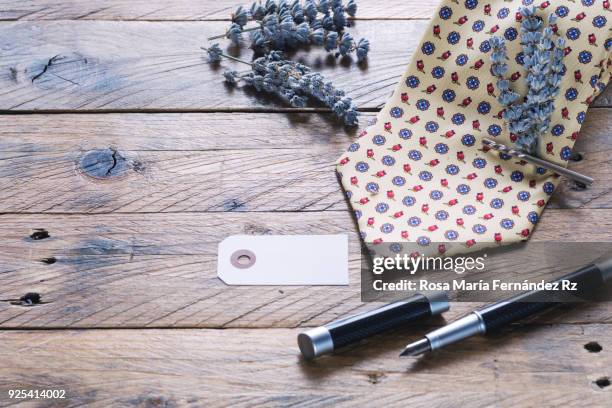 father's day concept. necktie with bouquet of lavender held with silver tie pin, blank greeting card for message and fountain pen on rustic wooden background. selective focus and copy space. - tie pin stock-fotos und bilder