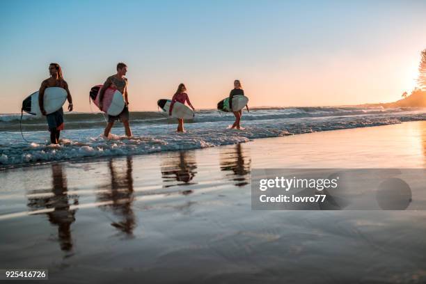 friends walking along the coast with surfboards - gold coast surfing stock pictures, royalty-free photos & images