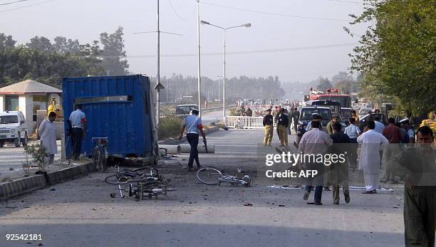 Pakistani security officials inspect the site after a suicide bomb attack in Kamra, near the Pakistan Aeronautical Complex on October 23, 2009....