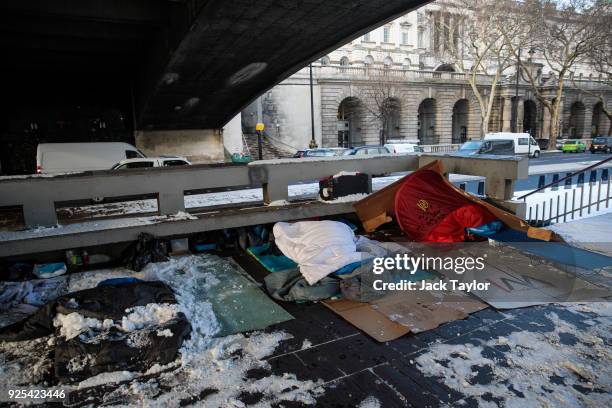 Bedding and shelters belonging to homeless people lie under a bridge covered in snow on the Embankment on February 28, 2018 in London, United...