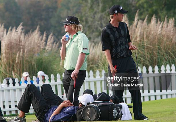 Caddies lie in wait on the practice green as PGA Tour golfers Charley Hoffman and Matt Jones of Australia wait for word on when first round play will...