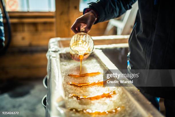 persoon gieten ahornsiroop op sneeuw op suiker shack - sugar stockfoto's en -beelden