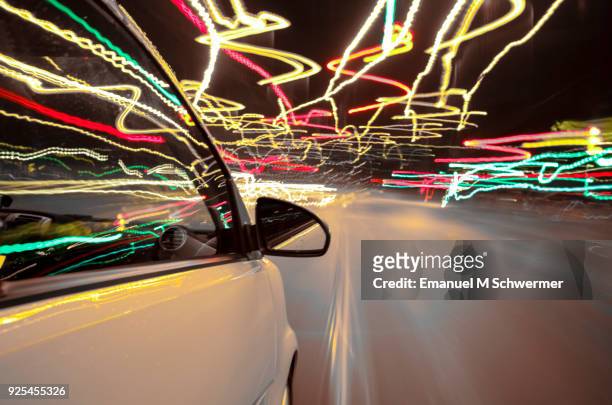 car drives through berlin while night - right side of the car with wing-mirror in foreground - long exposure - motorsport abstract stock pictures, royalty-free photos & images