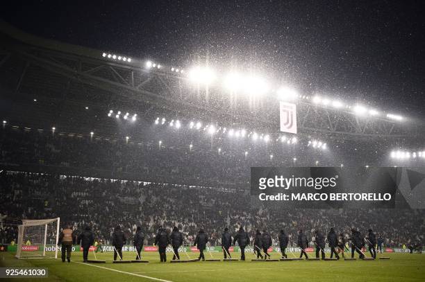 Groundstaff use brooms to sweep snow from the playing surface during the half-time break in the Italian Tim Cup football match between Juventus and...