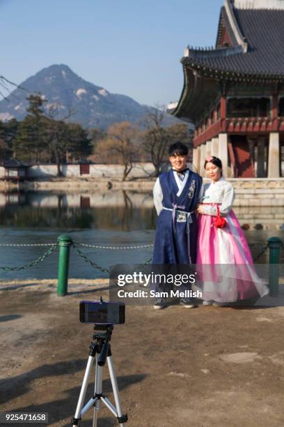 Young Korean couple in Hanbok's, traditional Korean dress, pose for a photo at the Gyeongbokgung Palace on 26th February 2018 in Seoul, South Korea....