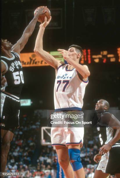 Gheorghe Muresan of the Washington Bullets looks to get his shot off over the top of David Robinson of the San Antonio Spurs during an NBA basketball...