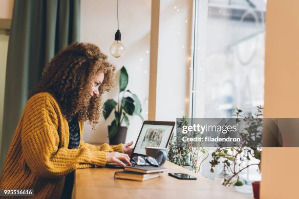 mujer joven trabajando en una computadora portátil - bloguear fotografías e imágenes de stock