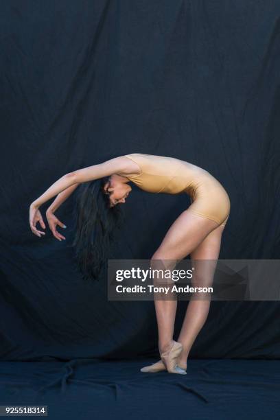 young woman ballet dancer against black background - huidkleurige schoen stockfoto's en -beelden