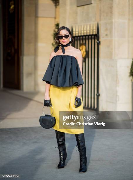 Olivia Culpo wearing a black off shoulder top Rochas, yellow Rochas skirt, Casadei boots, black Ferragamo bag, Le Specs sunglasses, earrings Andres...