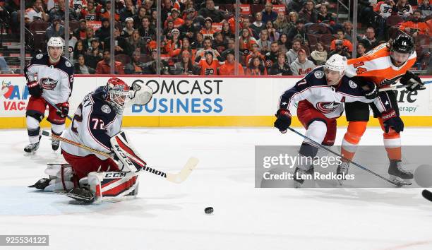 Sergei Bobrovsky of the Columbus Blue Jackets deflects a shot on goal as Jack Johnson defends Sean Couturier of the Philadelphia Flyers on February...