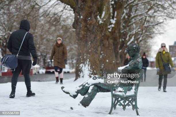 People pass by Patrick Kavanagh's statue near the Grand Canal during a snow shower this afternoon as the 'Beast from the East' has hit Ireland with...