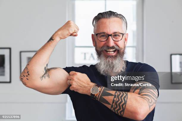 close up of smiling muscular caucasian hipster man flexing biceps - flexing muscles stockfoto's en -beelden