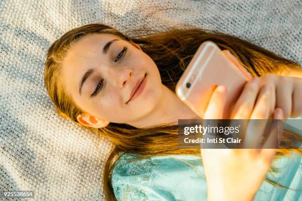 caucasian girl laying on blanket texting on cell phone - pré adolescente imagens e fotografias de stock