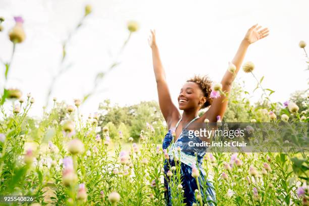 smiling mixed race woman celebrating in field of wildflowers - woman happy raised arms closed eyes stock pictures, royalty-free photos & images
