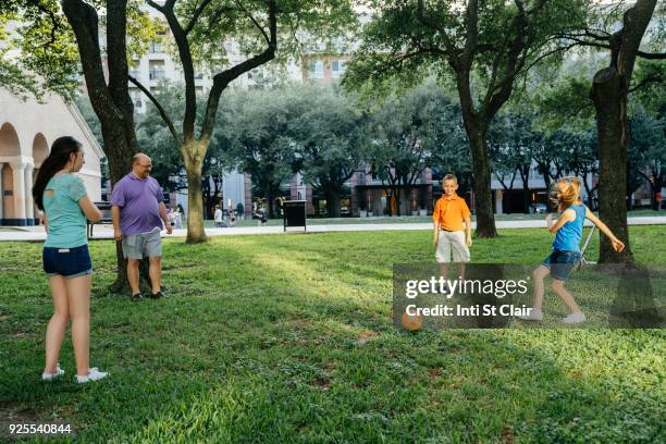 caucasian family kicking soccer ball in park - houston football stock pictures, royalty-free photos & images