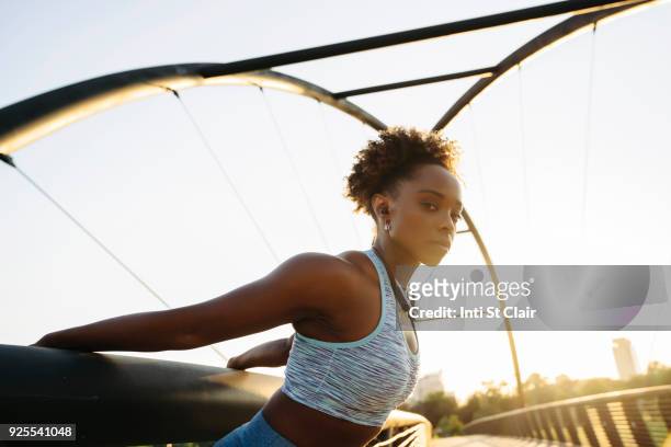 portrait of mixed race woman stretching arms by pulling on railing - will houston fotografías e imágenes de stock
