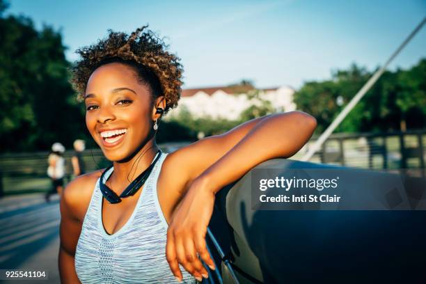 smiling mixed race woman listening to earbuds on bridge - só uma mulher de idade mediana - fotografias e filmes do acervo