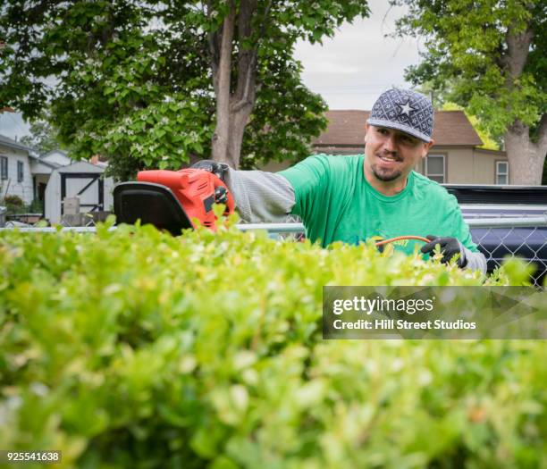 smiling volunteering man trimming hedges - hedge trimming stock pictures, royalty-free photos & images