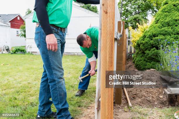 volunteering men repairing wooden fence - garden fence stock pictures, royalty-free photos & images