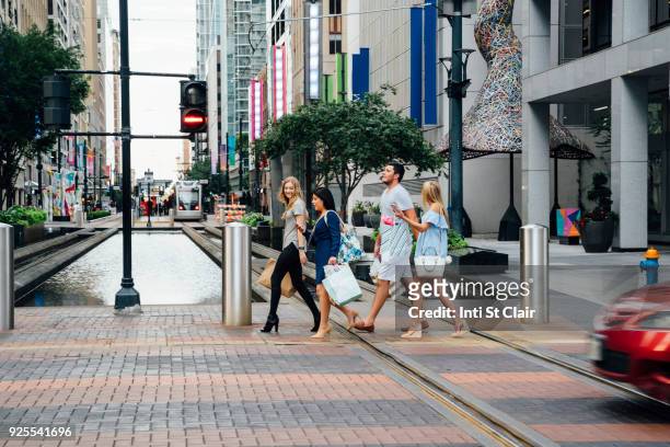 friends crossing street in city carrying shopping bags - houston people stock pictures, royalty-free photos & images