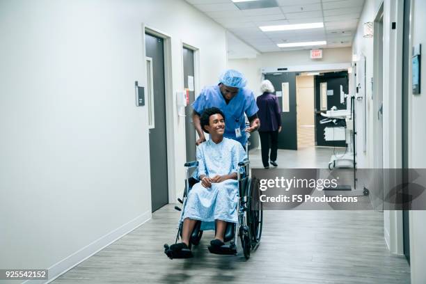 nurse pushing boy in wheelchair - surgeon walking stock pictures, royalty-free photos & images