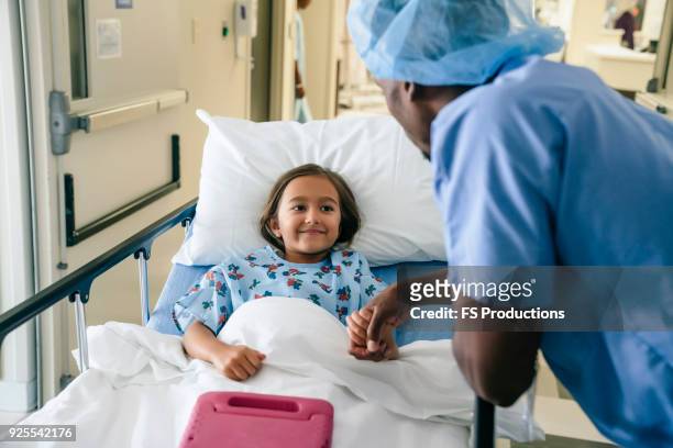 doctor holding hand of girl in hospital bed - criança enfermagem imagens e fotografias de stock