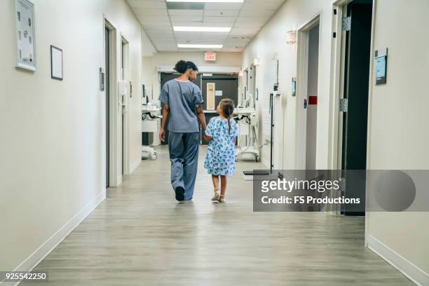 nurse walking with girl in hospital corridor - hopital couloir photos et images de collection