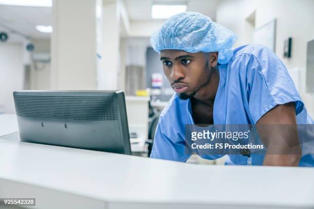 black doctor using computer in hospital - schwesterntisch stock-fotos und bilder
