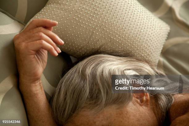 close-up view of woman's hand and streaked gray hair against sequined pillow and comforter - timothy hearsum stock-fotos und bilder
