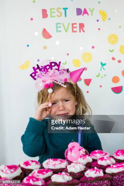 caucasian girl crying over tray of cupcakes for birthday - happy birthday crown foto e immagini stock