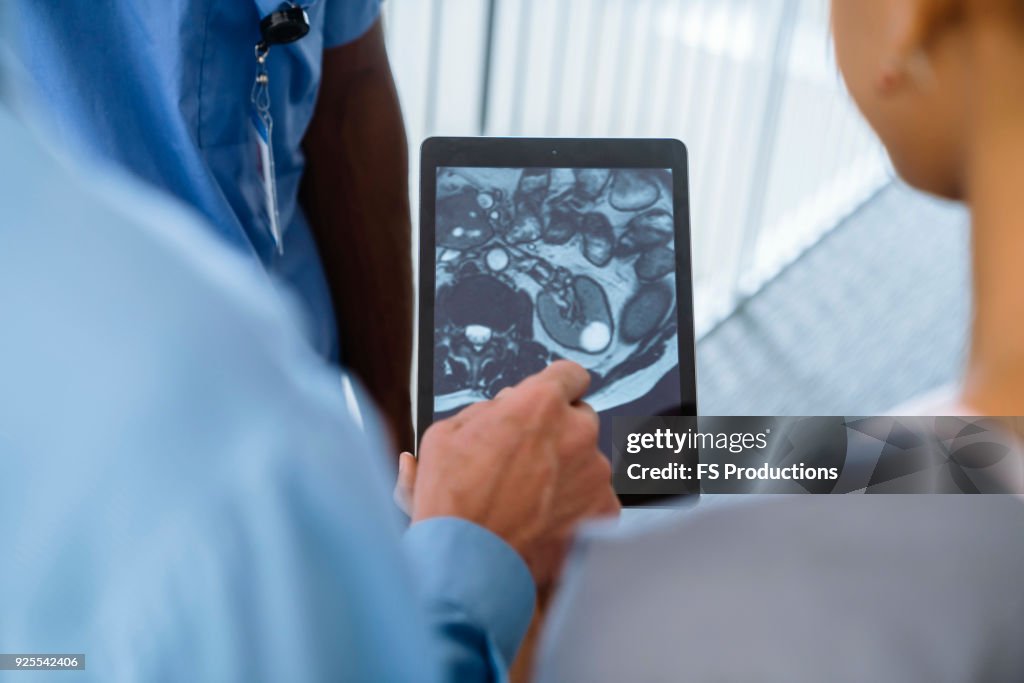Close up of doctor and nurses viewing image on digital tablet