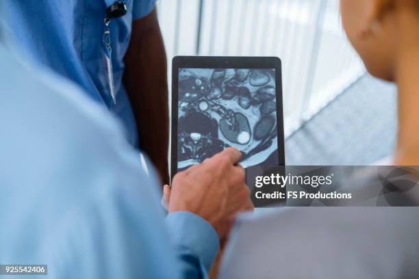 close up of doctor and nurses viewing image on digital tablet - doctor looking over shoulder stock pictures, royalty-free photos & images