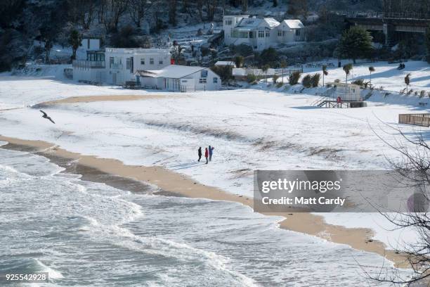 People walk on the snow covering the sand at Carbis Bay as snow arrives in St Ives on February 28, 2018 in Cornwall, England. Freezing weather...