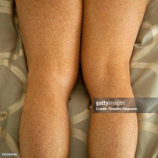 close-up view of the backs of a woman's thighs, knees and calves against a comforter - timothy hearsum stock-fotos und bilder