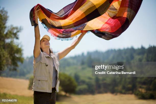 hispanic woman spreading picnic blanket outdoors - beautiful women spreading stock-fotos und bilder