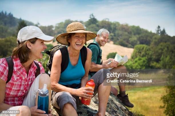 hikers siting on rock and laughing - vita attiva foto e immagini stock