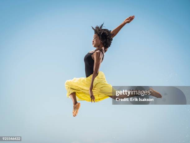 black woman dancing and jumping - black skirt stockfoto's en -beelden