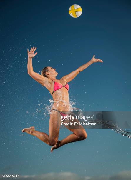 water splashing on caucasian woman jumping to volleyball - spiking stock-fotos und bilder