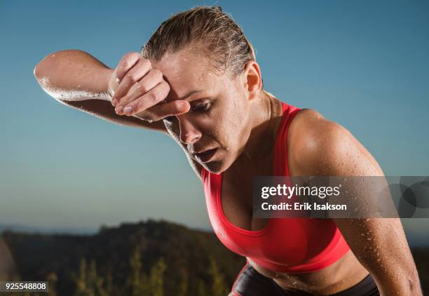 caucasian woman wiping sweat from forehead - warm up exercise stock-fotos und bilder