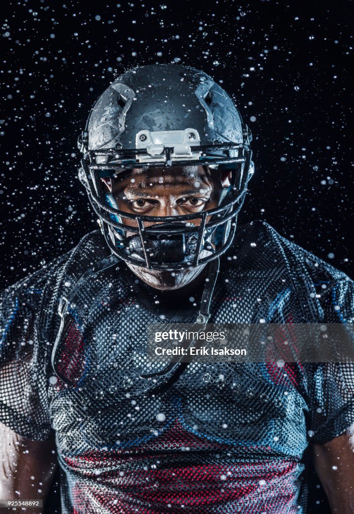 Water splashing on Black football player wearing helmet