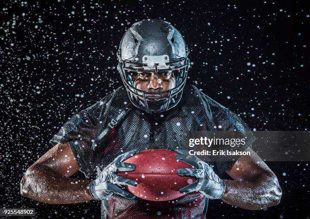 water splashing on black football player holding football - joueur de football américain photos et images de collection