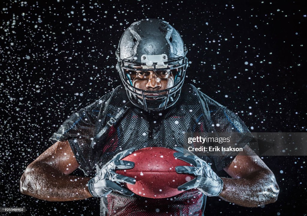 Water splashing on Black football player holding football