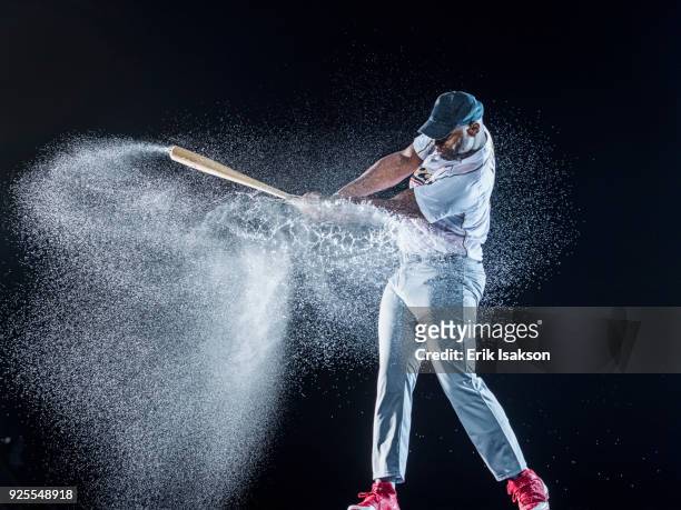 water splashing on black baseball player swinging bat - baseball bat swing stock pictures, royalty-free photos & images
