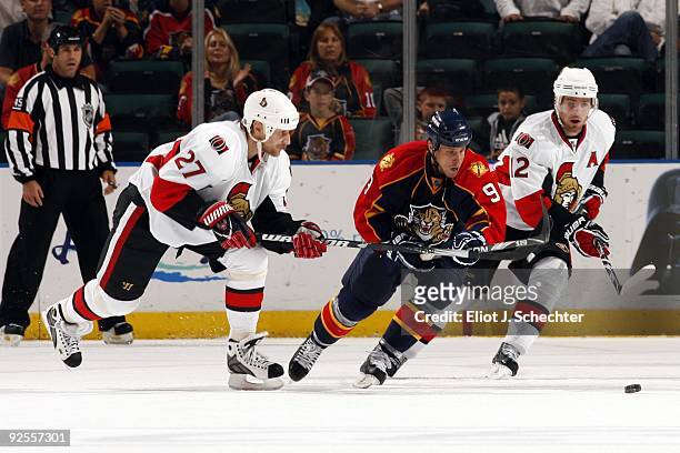 Mike Fisher of the Ottawa Senators and teammate Alex Kovalev tangle with Stephen Weiss of the Florida Panthers at the BankAtlantic Center on October...